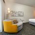 Courtyard by Marriott Dallas-Fort Worth/Bedford guest room with king bed and curved lounge chair