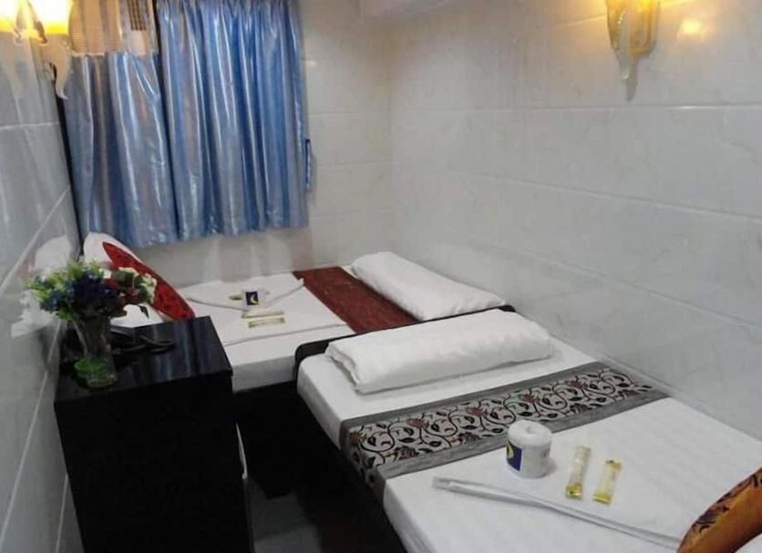 City Guest House in Hong Kong room with three single beds, blue curtains, and a small table