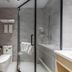 Tizi Hostel in Shanghai bathroom with glass shower enclosure, toilet, sink, and gray tile walls