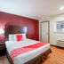 OYO Hotel Mcallen Airport South room with queen bed, red accent wall, lamp, chair and window in McAllen