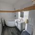 Hotel De l'Univers in Caen bathroom with corner bathtub, sink, toilet and striped vanity