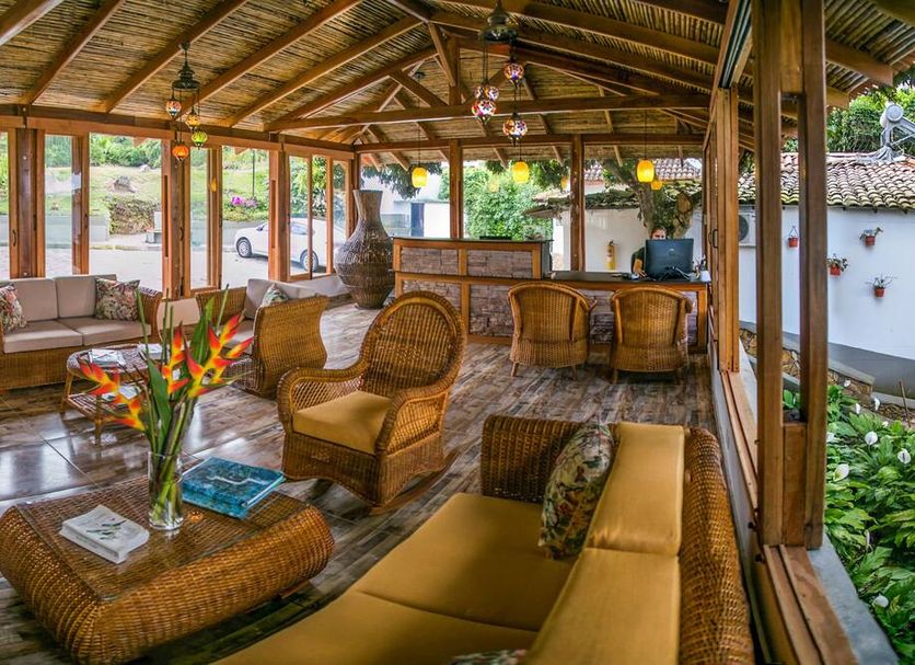 Hotel Spa La Colina in Pereira: open-air lounge with wicker seating, wood beams, and garden views