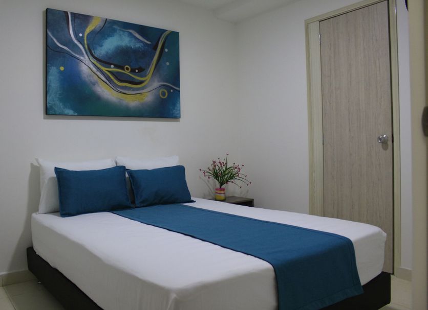 Hotel Pereira 421 room in Pereira with a double bed, blue bedding, wall art, and a bedside table.