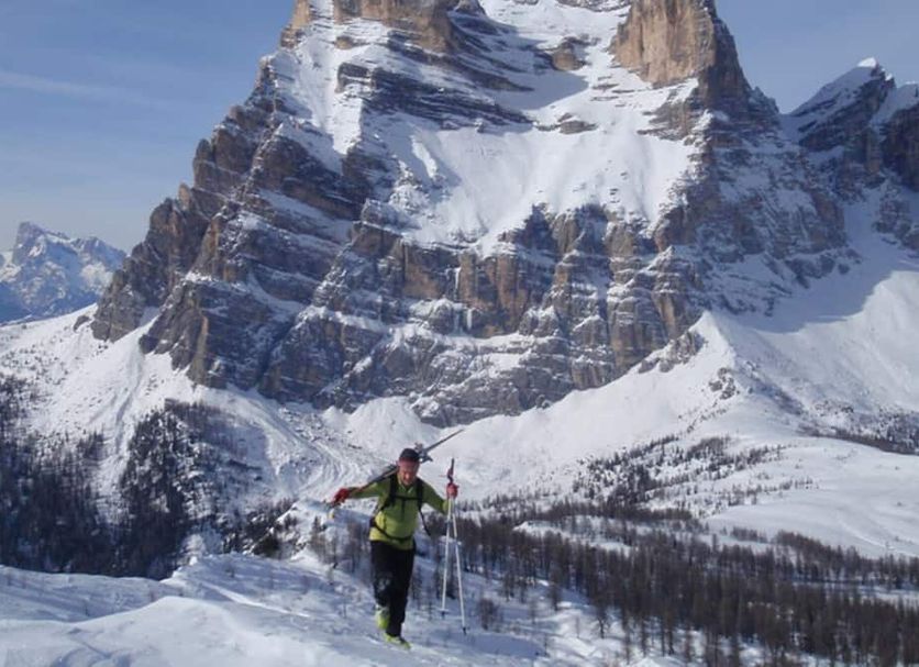 Hotel La Caminatha in Zoldo Alto with a skier in front of snowy Dolomite peaks