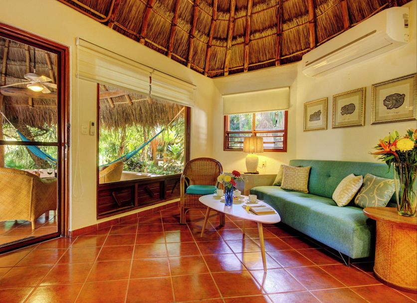 Riviera Maya Suites in Playa del Carmen, thatched-roof suite with teal sofa and tropical patio view
