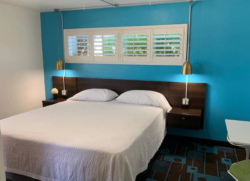 The Sands Motel in Boulder City room with bed, turquoise accent wall, and window shutters