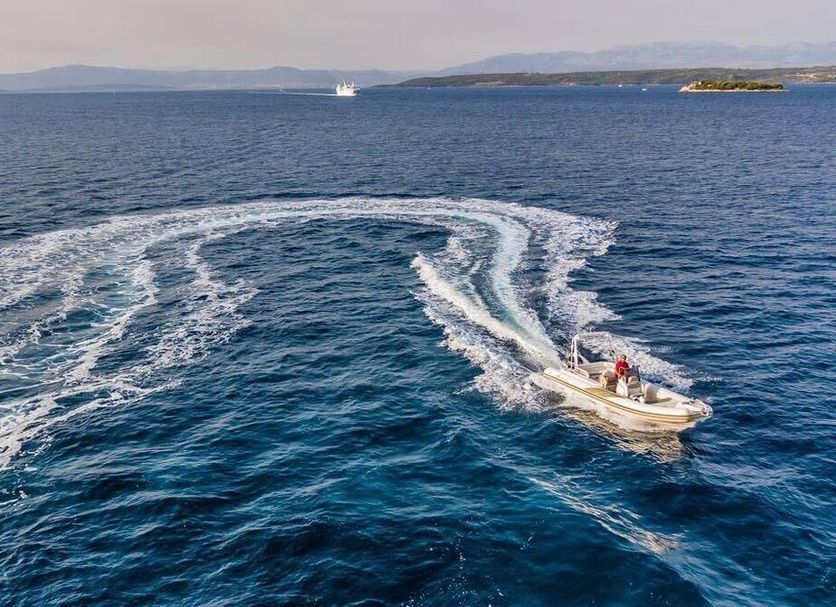 Hotel Podstine in Hvar with a speedboat on blue open water and a distant island shoreline