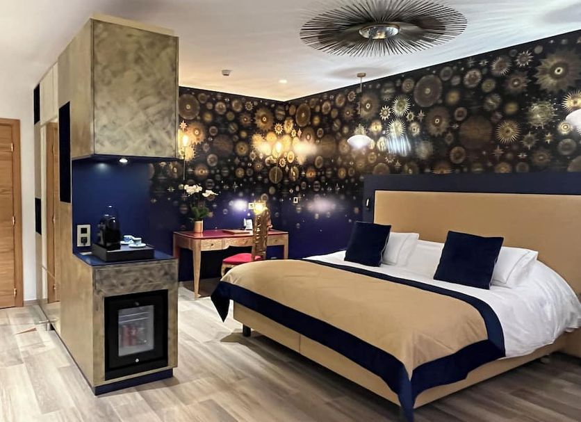 Hotel du Domaine de La Grange de Conde room with double bed, bold floral wallpaper, and small desk in Conde-Northen