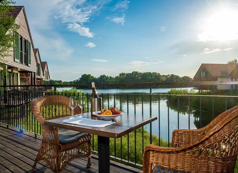 Tisza Balneum Hotel in Holló patio table and wicker chairs beside a lake at sunset