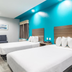 Scottish Inns & Suites - Kingwood in Humble with two white beds and a bright teal accent wall