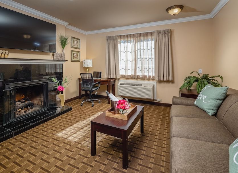Stage Coach Lodge, Monterey: guest lounge with fireplace, TV, sofa, desk, and window with blinds