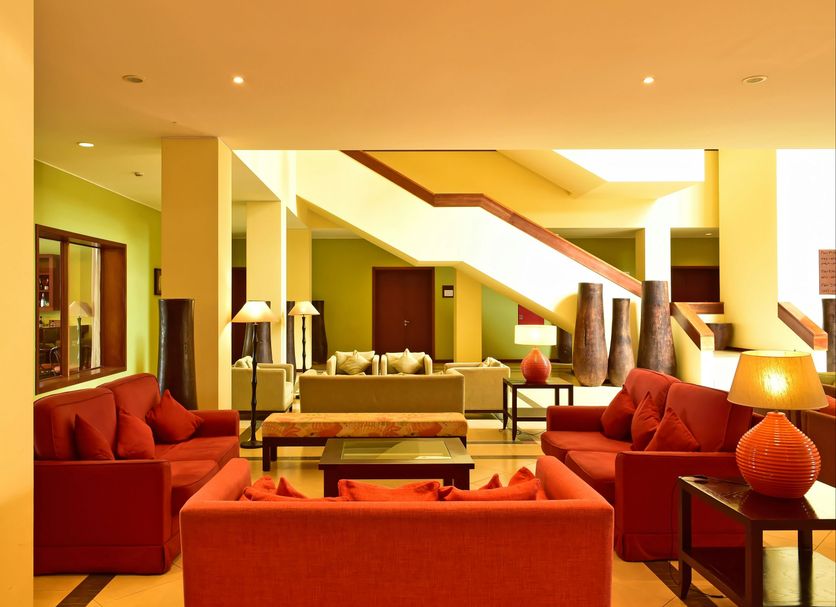 Pestana São Tomé lobby lounge with red sofas, staircase, and warm modern seating in São Tomé