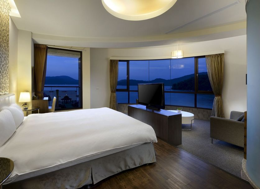 Hu Yue Lakeview Hotel in Nantou City guest room with lake view, king bed and large windows at sunset