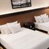 Hotel Mirage Brooklyn guest room with two double beds, wall art, lamp, and gray curtains in Brooklyn