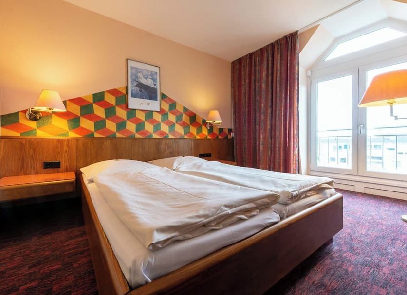 enjoyHotel garni Korntal Stuttgart guest room with double bed, bedside lamps and large window in Korntal-Münchingen