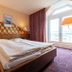 enjoyHotel garni Korntal Stuttgart guest room with double bed, bedside lamps and large window in Korntal-Münchingen
