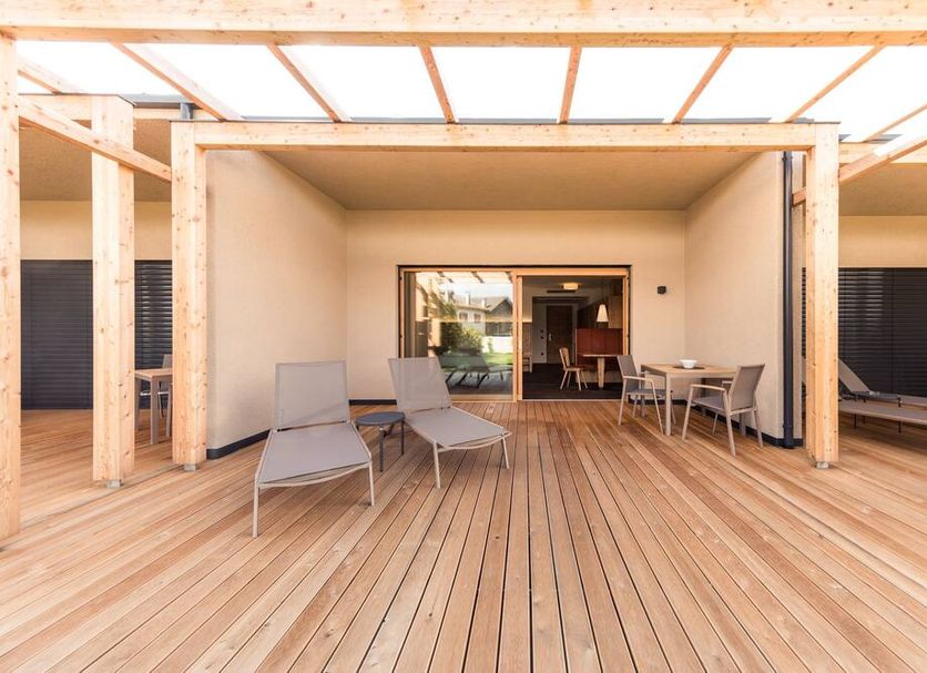 Weingut Moser Apartments in Caldaro, covered wooden terrace with lounge chairs and dining table