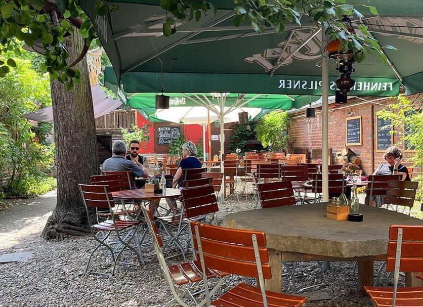 Homeplanet Hostel Leipzig outdoor courtyard seating with tables, chairs, and green umbrellas