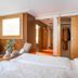 First Mountain Montafon in Gaschurn guest room with bed, sitting area, open wardrobe and wood-paneled walls