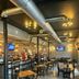 Hotel Whiskey in Pascagoula bar and dining area with tables, stools, exposed ductwork and TVs