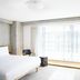 TUVE Hong Kong guest room with king bed, concrete walls, chair and large sheer-curtained window