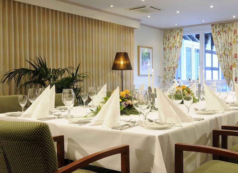 Vila Vita Burghotel Dinklage dining room set with a formal banquet table and floral curtains