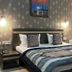 Hotel The Taksonz in Ludhiana guest room with a double bed, bedside tables, lamp, and patterned wallpaper