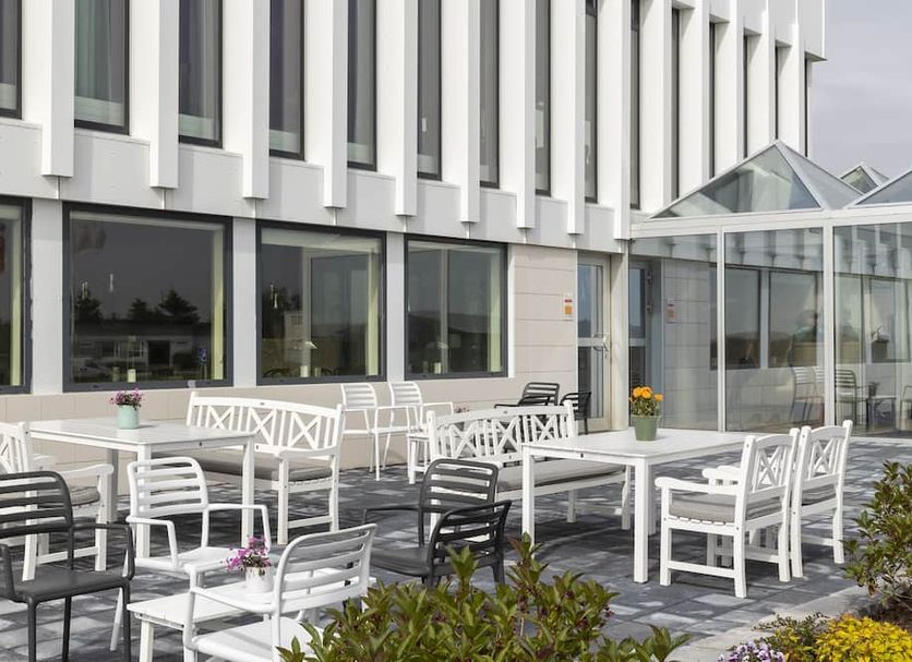 Hotel Höfn in Hofn: outdoor terrace with white tables and chairs beside a glass-enclosed building