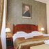 Mozart Hotel Szeged guest room with wooden bed, bedside lamps, dresser and wall portrait