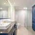Bhukitta Boutique Hotel Phuket City bathroom with marble walls, glass shower and blue cabinets