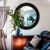 Mt Cotton Retreat in Mount Cotton: lounge with leather sofa, round mirror, potted plant and flowers