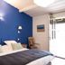 Oustau Camarguen Hôtel & Spa room with blue accent wall and open door in Le Grau-du-Roi