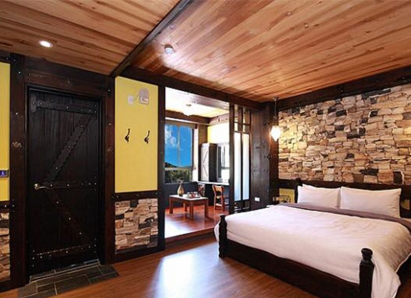 Youngquan Hotel in Yuchi Township bedroom with wooden ceiling, stone accent wall and mountain view