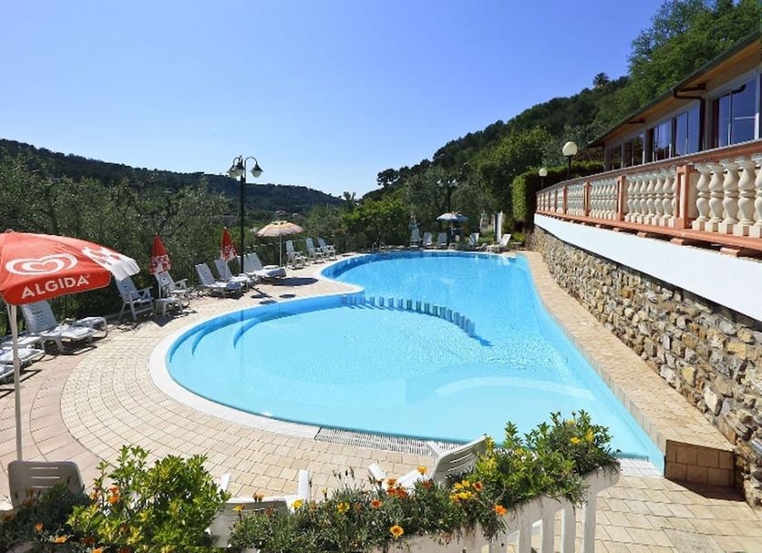 Poolside view at Albergo Ristorante San Matteo in San Bartolomeo al Mare with lounge chairs and hillside backdrop