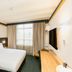 Statesman Hotel Canberra guest room with double bed, window light, desk, and wall-mounted TV