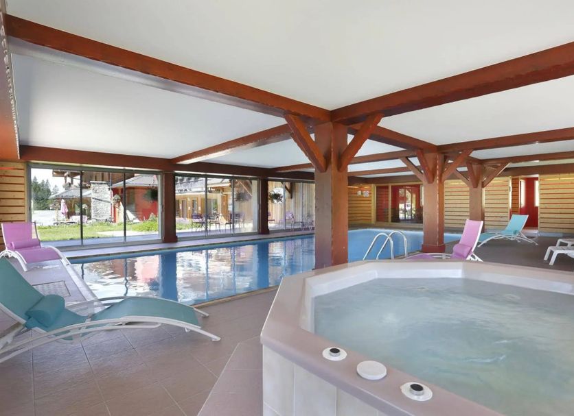Les Roches 1500 in Taninges indoor pool with a hot tub, lounge chairs and large windows