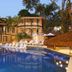 Porto Pacuíba Hotel in Ilhabela with a lit pool, lounge chairs, palm trees, and tropical resort buildings