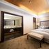 Jeju Sun Hotel & Casino in Jeju City guest room with king bed, bench, and warm ceiling lighting