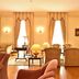 Pousada Palácio de Queluz lounge with armchairs, fireplace, and tall draped windows in Queluz