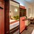 StayEasy Pretoria hotel room with bed, desk, mirror wardrobe and curtained window in Pretoria