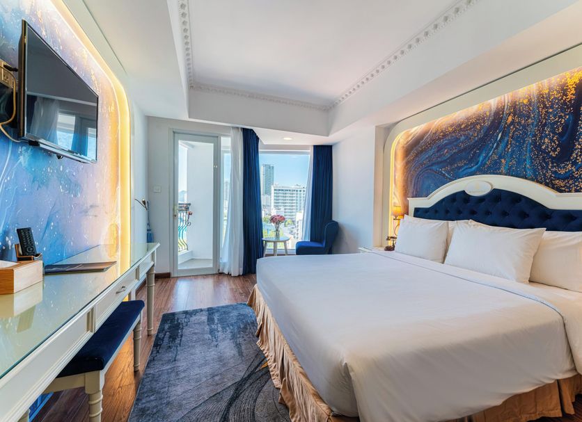Nha Trang Prince Hotel room with king bed, balcony door, and city view in Nha Trang