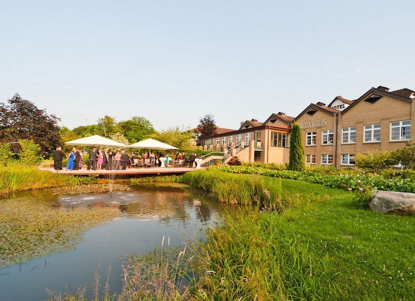 Romantik Hotel Waldschlösschen in Schleswig with pond, lawn, and outdoor terrace by the hotel