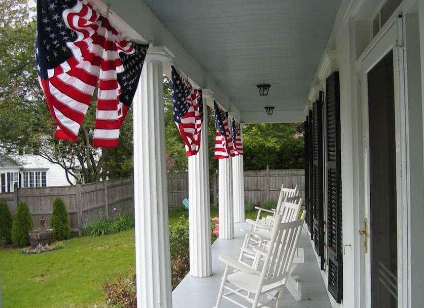 Liberty Hill Inn in Yarmouth porch with white rocking chairs and American flags hanging along the columns