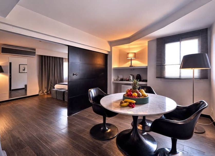 Bab Hotel Marrakech suite with dining table, black chairs, bedroom alcove and window lamp