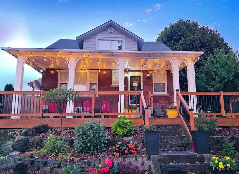 Serene Niagara Inn in Niagara Falls with a porch, string lights, and landscaped garden at dusk