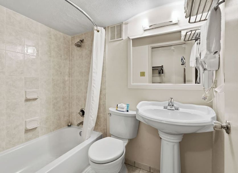 Executive Inn - Fort Lee bathroom with tub-shower combo, pedestal sink, mirror, and toilet