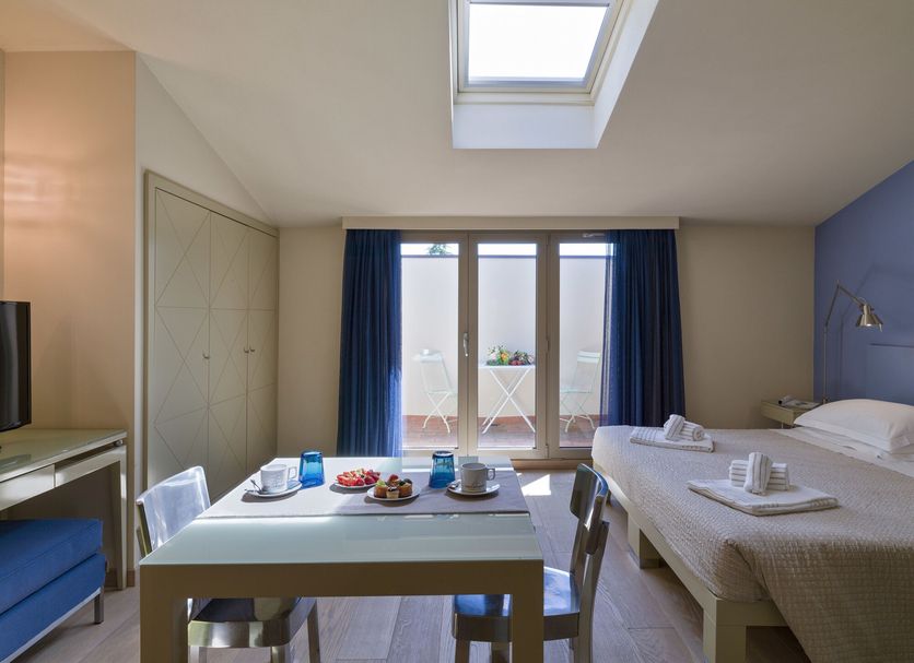 Popartment Florence room with skylight, table setting, and bed by balcony doors