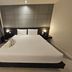 The Park Residence Bangkok guest room with queen bed, bedside lamps and gray paneled headboard