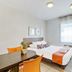 Appart'City Classic Thonon Les Bains room with bed, desk, window and orange chairs in Thonon-les-Bains