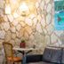 Casa Nostra Boutique Hotel in Paraty: cozy lounge with stone wall, wall sconce, sofa and colorful painting
